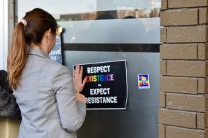 Vrouw plakt sticker tegen LHBT+ discriminatie op
