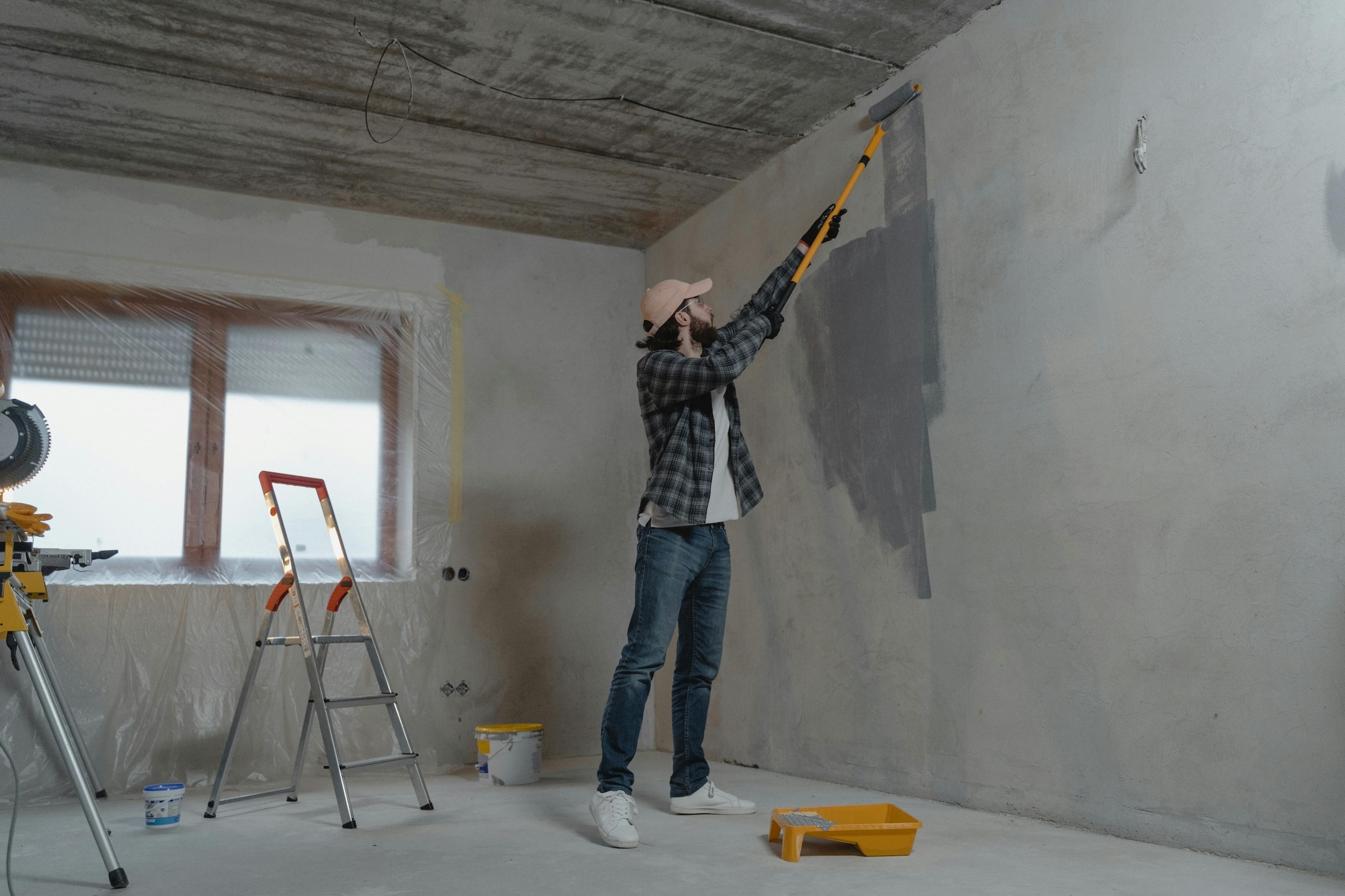 Een witte man met baard schildert de muur van zijn nieuwe huis