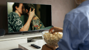 Vrouw kijkt naar een televisie waarop twee mannen aan het zoenen zijn.