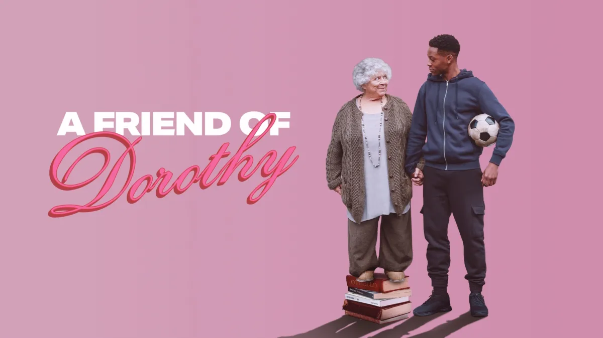 Banner met daarop de titel van de film, 'A Friend of Dorothy'. Dorothy staat op een stapel boeken, houdt de hand van JJ vast die ernaast staat met een voetbal onder zijn arm.