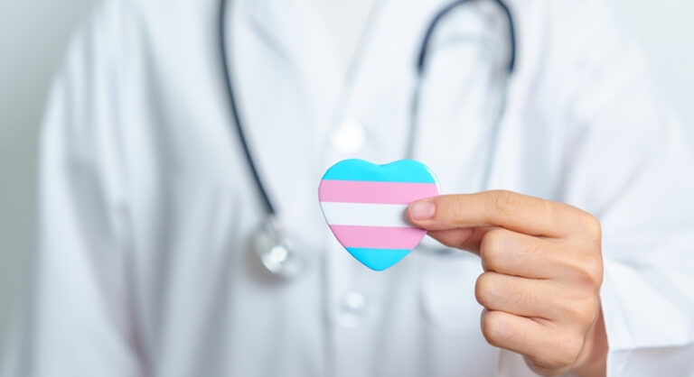 Arts die een hartje met de transgender vlag naar voren houdt.